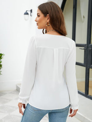 White textured pleat-front blouse with ruffle cuffs and long sleeves.
