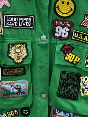 Green denim trucker jacket with embroidered patches including a tiger, smiley face, and text.