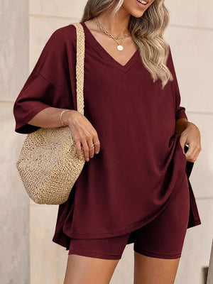 Burgundy V-neck two-piece set with loose-fit top and biker shorts, styled with a straw bag.