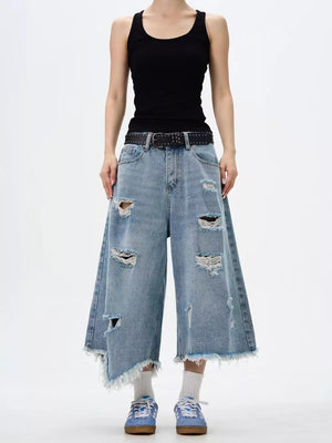 Distressed light wash wide-leg jeans with raw hem and ripped details.