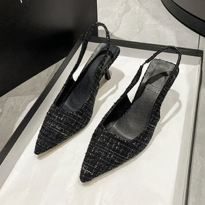 Black tweed slingback kitten heels with pointed toe and elastic strap.