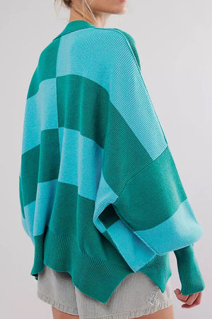 Checkerboard knit oversized sweater in turquoise and green with a collar and wide sleeves.
