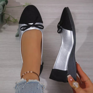 Silver and black slip-on flats with bow detail, comfortable casual footwear.