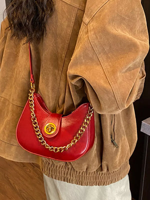 Crescent shoulder bag in wine red with gold chain accent and turn-lock closure.