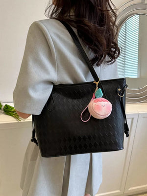 Black textured diamond woven tote bag with a pink charm and blue accent.