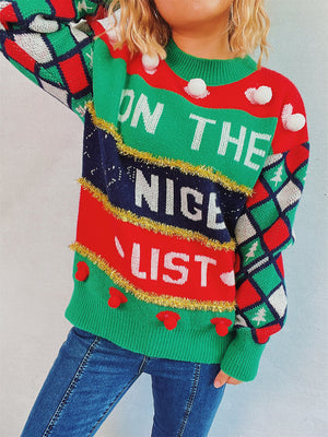 Green crewneck sweater with "ON THE NICE LIST" graphic, pom-poms, and diamond pattern sleeves.