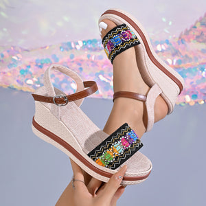 Embroidered floral wedge sandals in beige with adjustable ankle strap and brown trim.