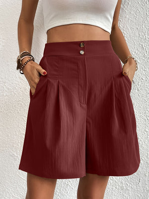 Burgundy pleated front bermuda shorts with button closure and side pockets.