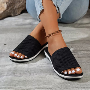 Black open-toe knit slide sandals with white-trimmed soles.