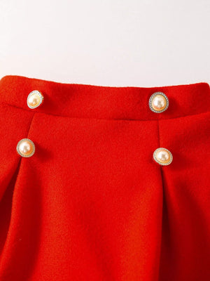 Red knit baby skirt with pearl and rhinestone buttons and pleats.