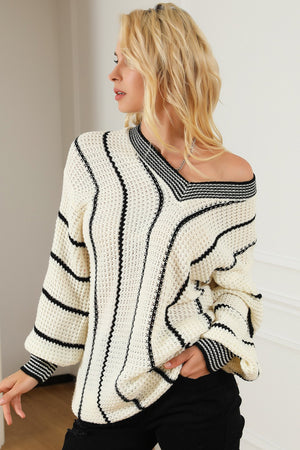 Ivory knit oversized V-neck sweater with black vertical stripes and banded cuffs.