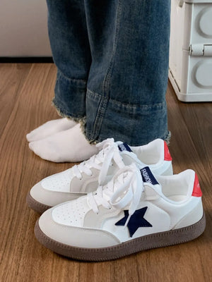 White retro sneakers with navy star appliqué and red heel detail.