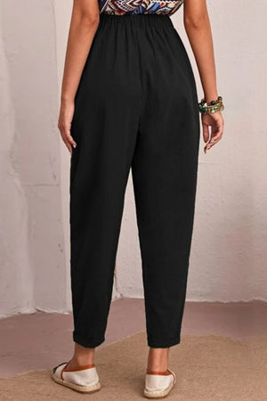 Black linen tapered trousers with elastic waist and cuffed hem.