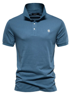 Peacock Blue cotton polo shirt with embroidered crest detail and button collar.
