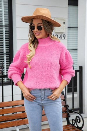 Pink fluffy mock neck sweater with long sleeves, styled casually with jeans.