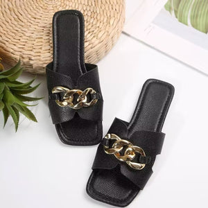 Black chain-embellished slide sandals with textured faux leather and gold hardware.