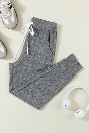 Slim-fit dark gray heathered joggers with white drawstring and cuffed ankles.
