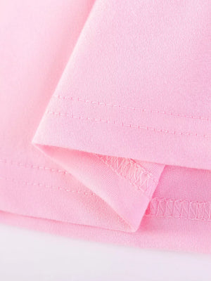 Pink cotton baby dress detail showing seams and fabric texture.