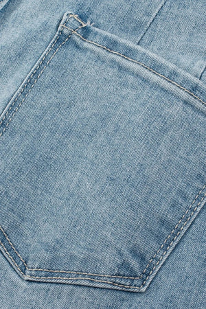 Button-fly wide-leg denim trousers in medium wash, showing a detailed view of a back pocket with contrast stitching.