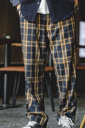 Men's relaxed fit sweatpants in black and mustard plaid with elastic waist.