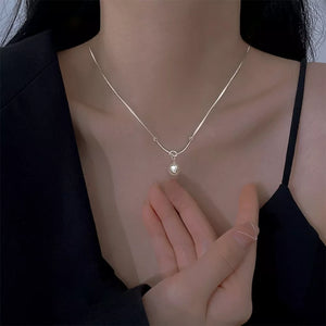 Silver pendant necklace with a lustrous pearl detail on a delicate chain.