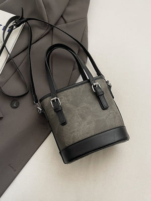 Premium two-tone bucket crossbody bag with black trim and silver buckle details.