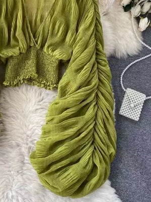 Green ruched sleeve blouse with V-neck and smocked waist detail.