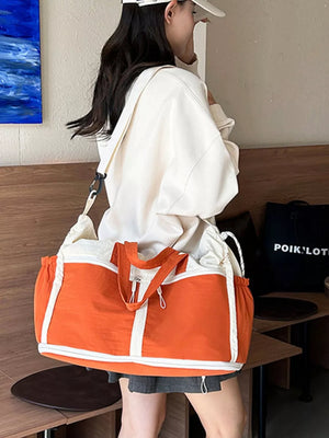 Vibrant color-block travel bag with orange and white panels, drawstring sides, and dual handles.