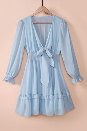 Sky blue mini dress with V-neck, bow-tie waist, smocked waist, and ruffled hem.