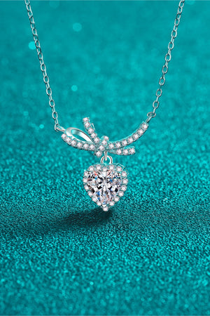Silver necklace with heart-shaped cubic zirconia pendant and bow accent.