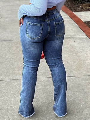 Distressed flare jeans in dark blue denim with a raw hem detail.