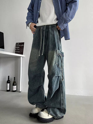 Relaxed fit blue denim cargo jeans with drawstring waist and zippered pocket detail.