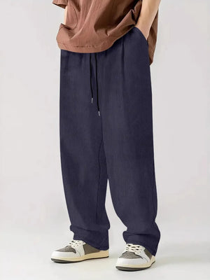 Indigo corduroy relaxed fit trousers with drawstring waist and vertical texture.