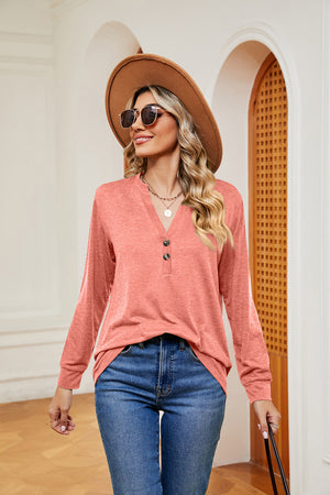 Henley-inspired long sleeve top in coral with button placket and V-neck, styled with jeans.