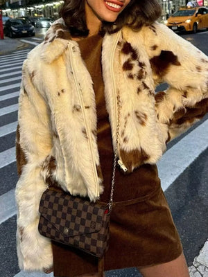 Cropped faux fur zip up jacket in beige with brown spots, featuring a cream zipper and collar.