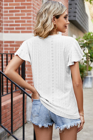 White eyelet blouse with flutter sleeves and a textured pattern, paired with denim shorts.