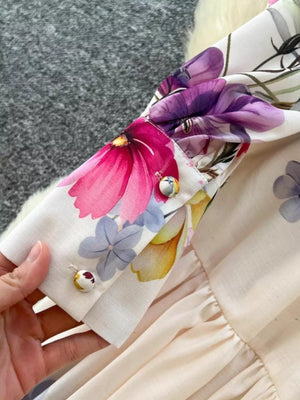 Vibrant floral midi dress with buttoned cuffs and ruffled hem detail.