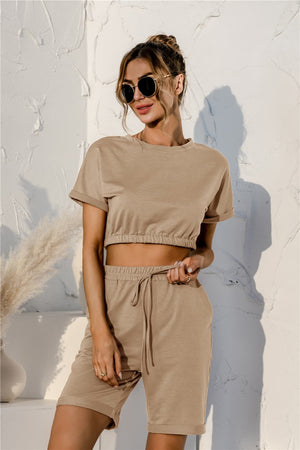 Tan loungewear set with cropped tee and drawstring shorts, featuring rolled sleeves and cuffed hems.