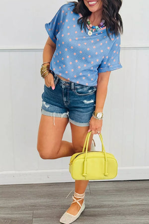 Blue ribbed knit tee with pink polka dots, cuffed short sleeves, and a crew neck.