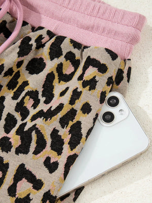 Leopard print loungewear pants with pink drawstring waist and side pocket holding a phone.