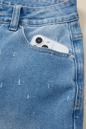 Blue denim jeans with distressed details and a phone in the pocket.