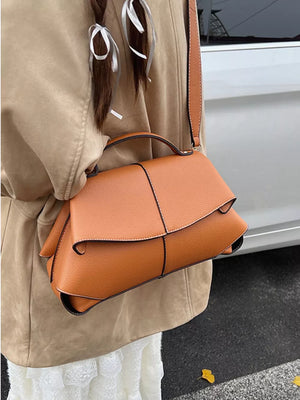 Brown textured geometric flap shoulder bag with top handle and adjustable strap.