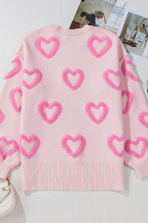 Pink knit sweater with allover textured heart appliques and balloon sleeves.