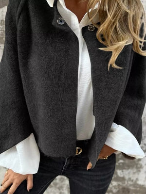 Black fuzzy knit cardigan with button detail, open front, worn over white shirt.