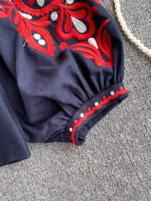 Navy peasant blouse with red and white embroidery on sleeve and neckline detail.