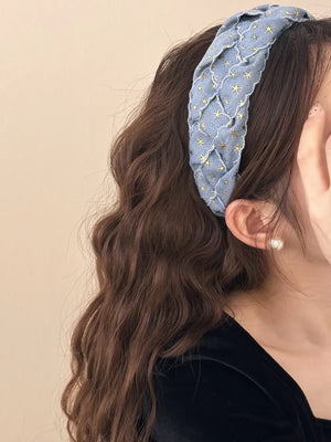 Braided denim headband with gold stars, featuring a woven texture.
