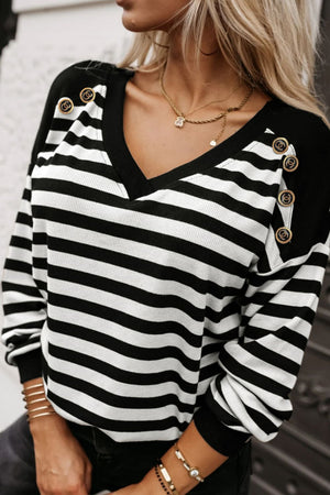 Black and white striped blouse with V-neck and decorative gold buttons on shoulders.