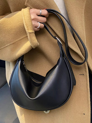 Black minimalist crescent crossbody bag with adjustable strap and zip closure.