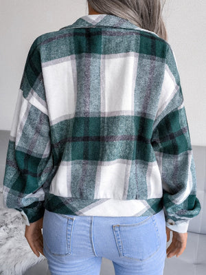 Oversized dark green tartan shacket with buttoned cuffs and collar, worn with jeans.