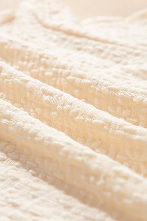 Beige blouse with textured fabric and ruffle hem detail.